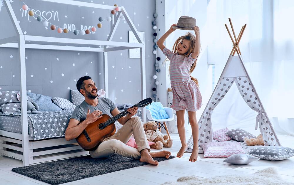 Father playing the guitar for his young daughter as she dances.