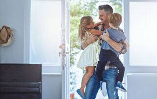 Excited son and daughter greeting dad as he come home